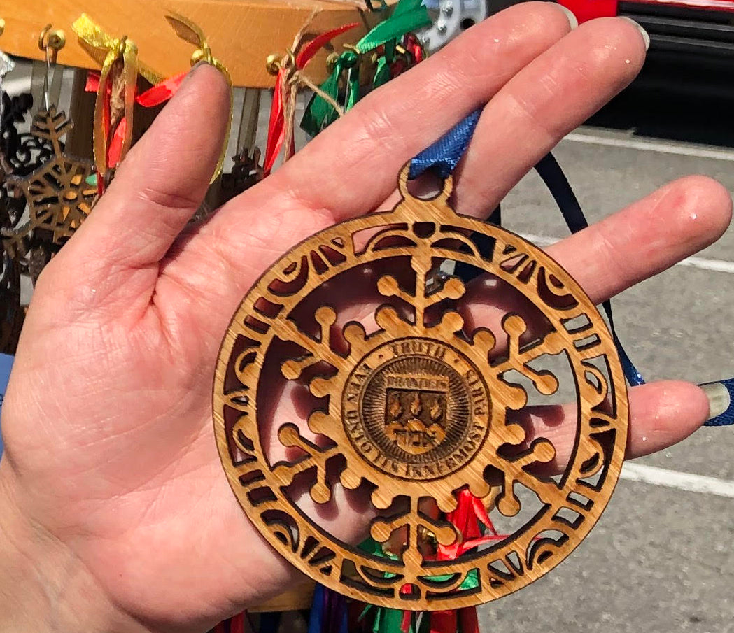 The Brandeis University Seal Christmas Ornament is laser cut into mahogany by a local artisan, Calile's Creations.  Brandeis Christmas Ornament.