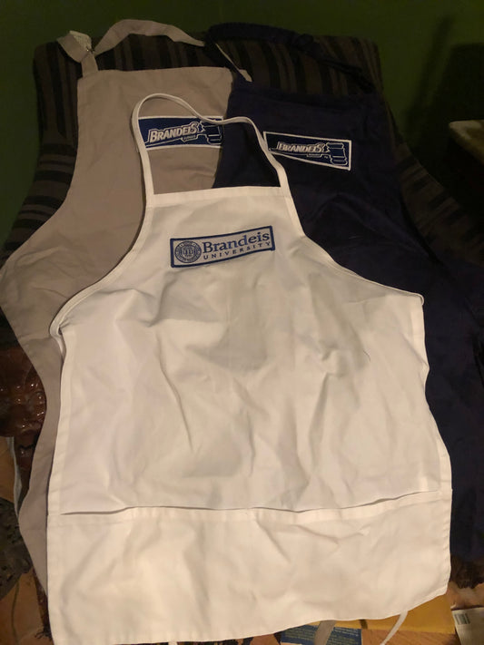 Cotton canvas cooking aprons in adult sizes are branded with a fully embroidered Brandeis University Gavel Logo